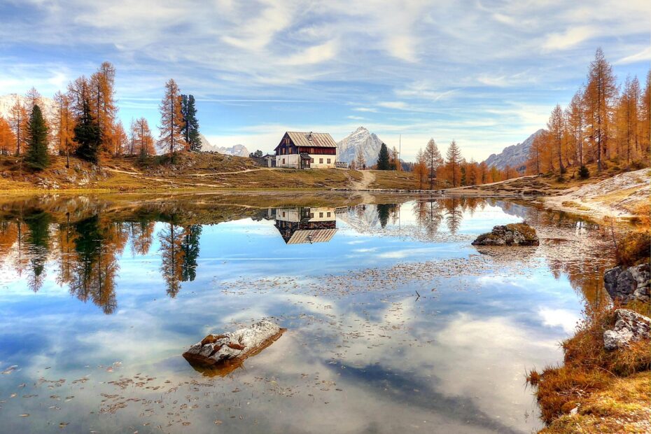 una foto di un rifugio di montagna che si riflette in uno specchio d'acqua