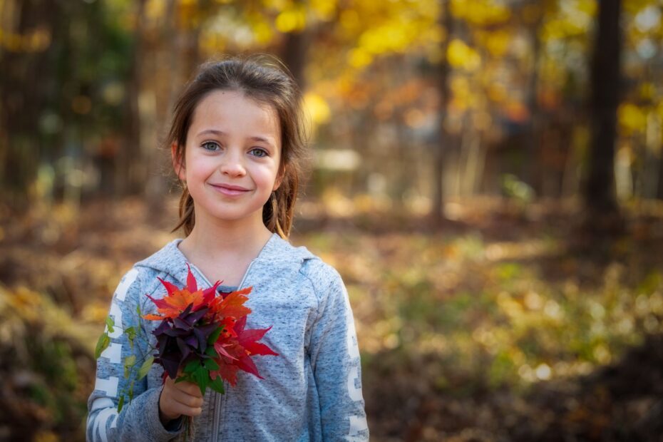 Una bambina gioca con delle foglie in mano