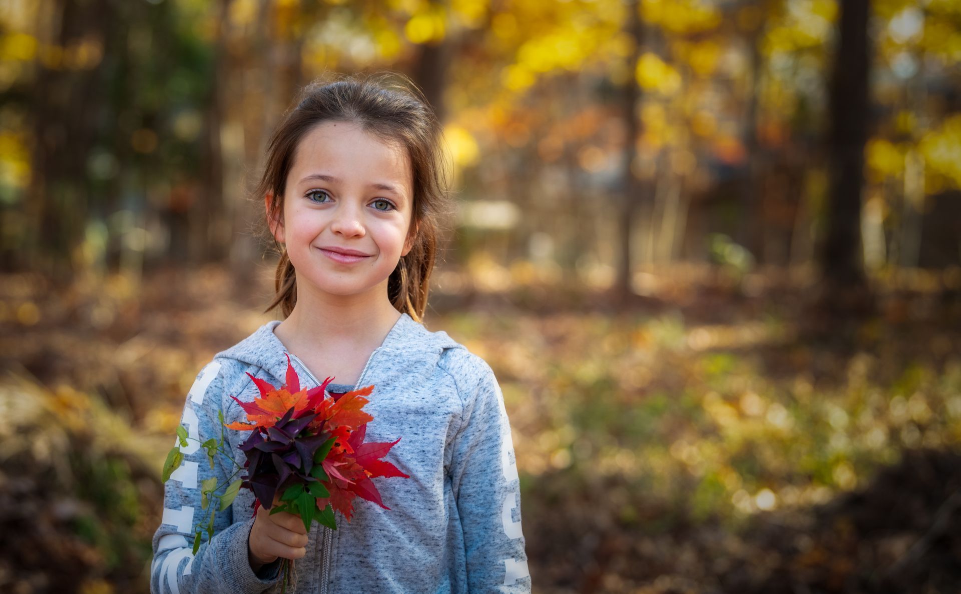 Una bambina gioca con delle foglie in mano